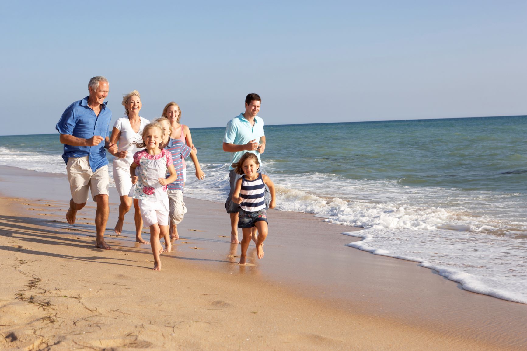family running on sunny beach 