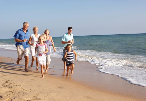 family running on sunny beach 